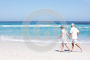 Senior Couple On Holiday Running Along Sandy Beach