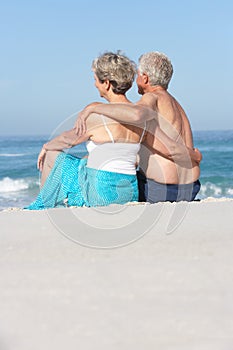 Senior Couple On Holiday Sitting On Sandy Beach