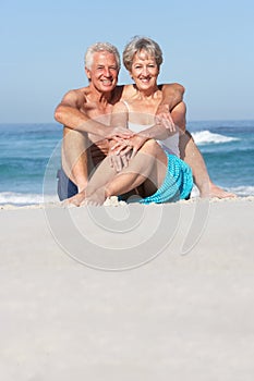 Senior Couple On Holiday Sitting On Sandy Beach