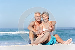 Senior Couple On Holiday Sitting On Sandy Beach