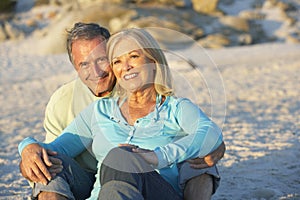 Senior Couple On Holiday Sitting On Sandy Beach