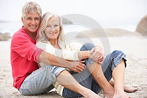 Senior Couple On Holiday Sitting On Winter Beach