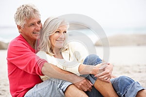 Senior Couple On Holiday Sitting On Winter Beach