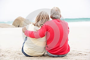Senior Couple On Holiday Sitting On Winter Beach
