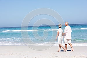 Senior Couple On Holiday Walking Along Sandy Beach