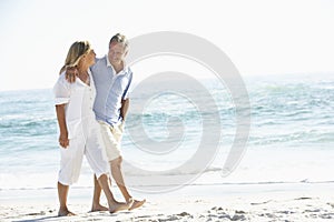 Senior Couple On Holiday Walking Along Sandy Beach