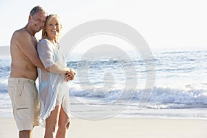 Senior Couple On Holiday Walking Along Sandy Beach