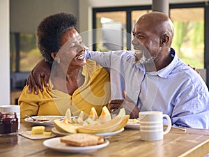 Senior Couple At Home Enjoying Breakfast Around Table Together