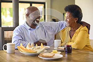 Senior Couple At Home Enjoying Breakfast Around Table Together