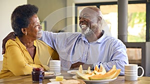 Senior Couple At Home Enjoying Breakfast Around Table Together