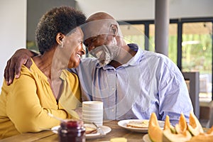 Senior Couple At Home Enjoying Breakfast Around Table Together