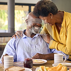 Senior Couple At Home Enjoying Breakfast Around Table Together