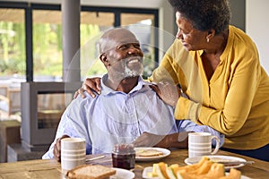 Senior Couple At Home Enjoying Breakfast Around Table Together