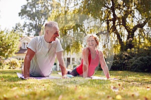 Senior Couple At Home In Garden Wearing Fitness Clothing Enjoying Outdoor Yoga Class