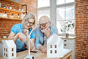 Senior couple with house models and toy wind turbine at home