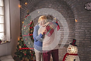 Senior couple hugging while exchanging Christmas gifts