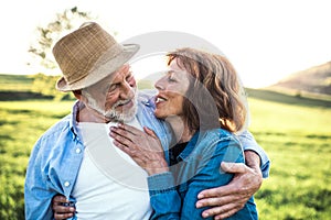 Senior couple hugging outside in spring nature.