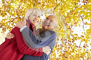 Senior Couple Hugging Underneath Autumn Tree