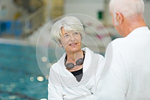 senior couple at indoor pool wearing bathrobes