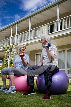 Senior couple interacting while exercising with dumbbells