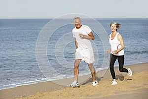 Senior Couple Jogging Along Beach