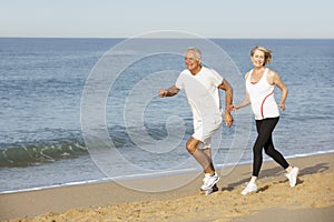 Senior Couple Jogging Along Beach