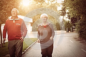 Senior couple jogging in city park.