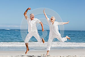 Senior couple jumping at the beach