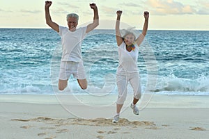 Senior couple jumping on seashore