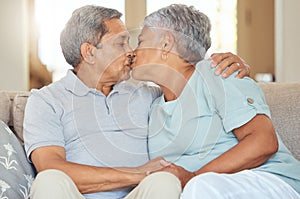 Senior couple, kiss and love at home while sitting on sofa in lounge to bond, relax and enjoy free time during