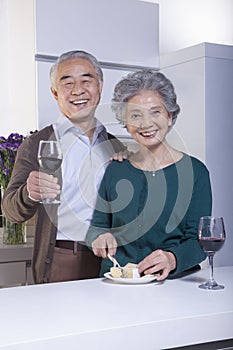 Senior Couple in Kitchen Drinking Wine and Cheese