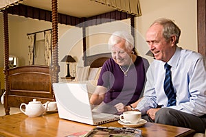 Senior couple with laptop in hotel bedroom