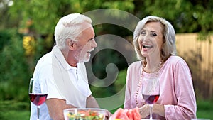 Senior couple laughing at dining table, telling funny jokes, remembering moments