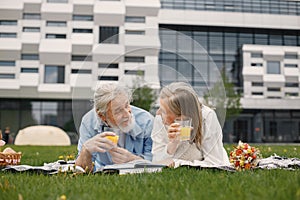 Senior couple laying on a blanket on a picnic in summer and reading a book