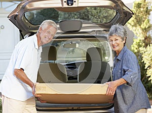 Senior Couple Loading Large Package Into Back Of Car