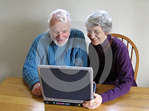 senior couple look at laptop