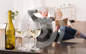 Senior Couple Looking Album, Drinking Wine At Home