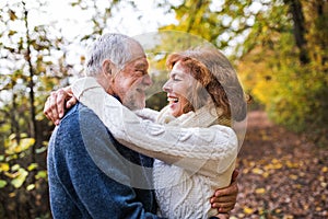 Senior couple looking at each other in an autumn nature, hugging.