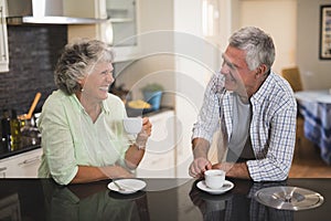 Senior couple looking at each other while having coffee at home