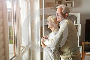 Senior couple looking out living room window