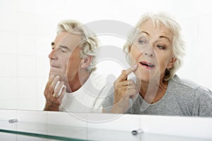 Senior Couple Looking At Reflections In Mirror For Signs Of Ageing