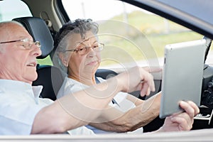 Senior couple looking at tablet in vehicle