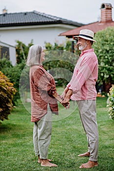 Senior couple in love posing together in their garden, holding each other hands.
