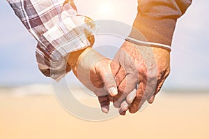 Senior couple in love walking at the beach holding hands