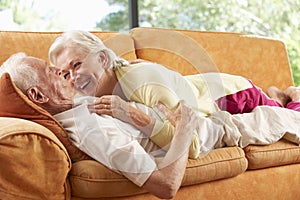 Senior Couple Lying On Sofa At Home