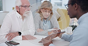 Senior couple with a male financial advisor by a table in the dining room of their modern house. Conversation, meeting