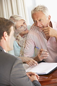 Senior Couple Meeting With Financial Advisor At Home Looking Worried