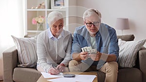 Senior couple with money and bills at home