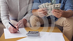 Senior couple with money and bills at home