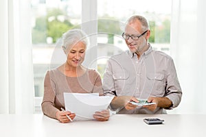 Senior couple with money and calculator at home
